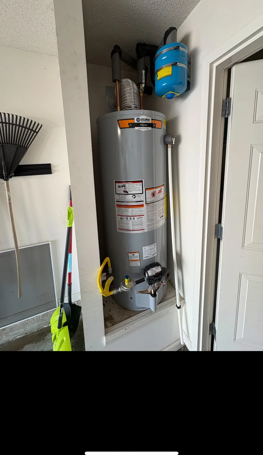 New gas water heater with expansion tank installed in a garage closet